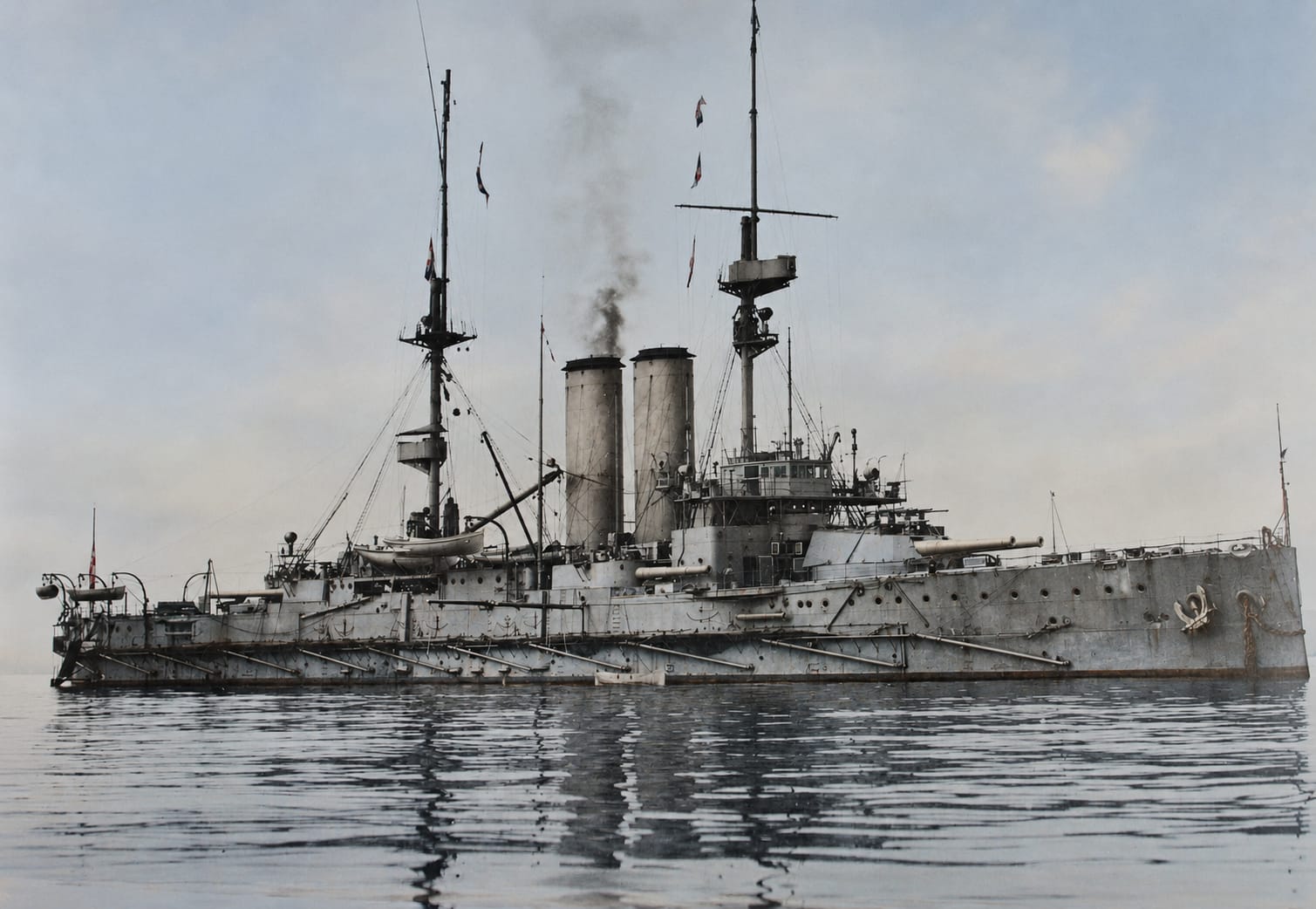 A King Edward VII-class pre-dreadnought battleship at anchor, her mixed battery of heavy turrets and casemate guns ranged along the hull